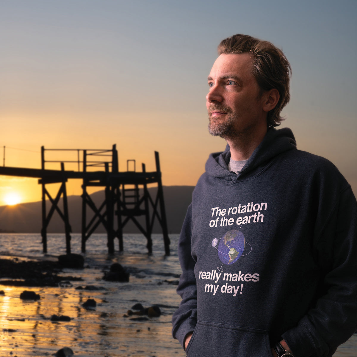 The Rotation Of The Earth Really Makes My Day hoodie on a beach at sunset